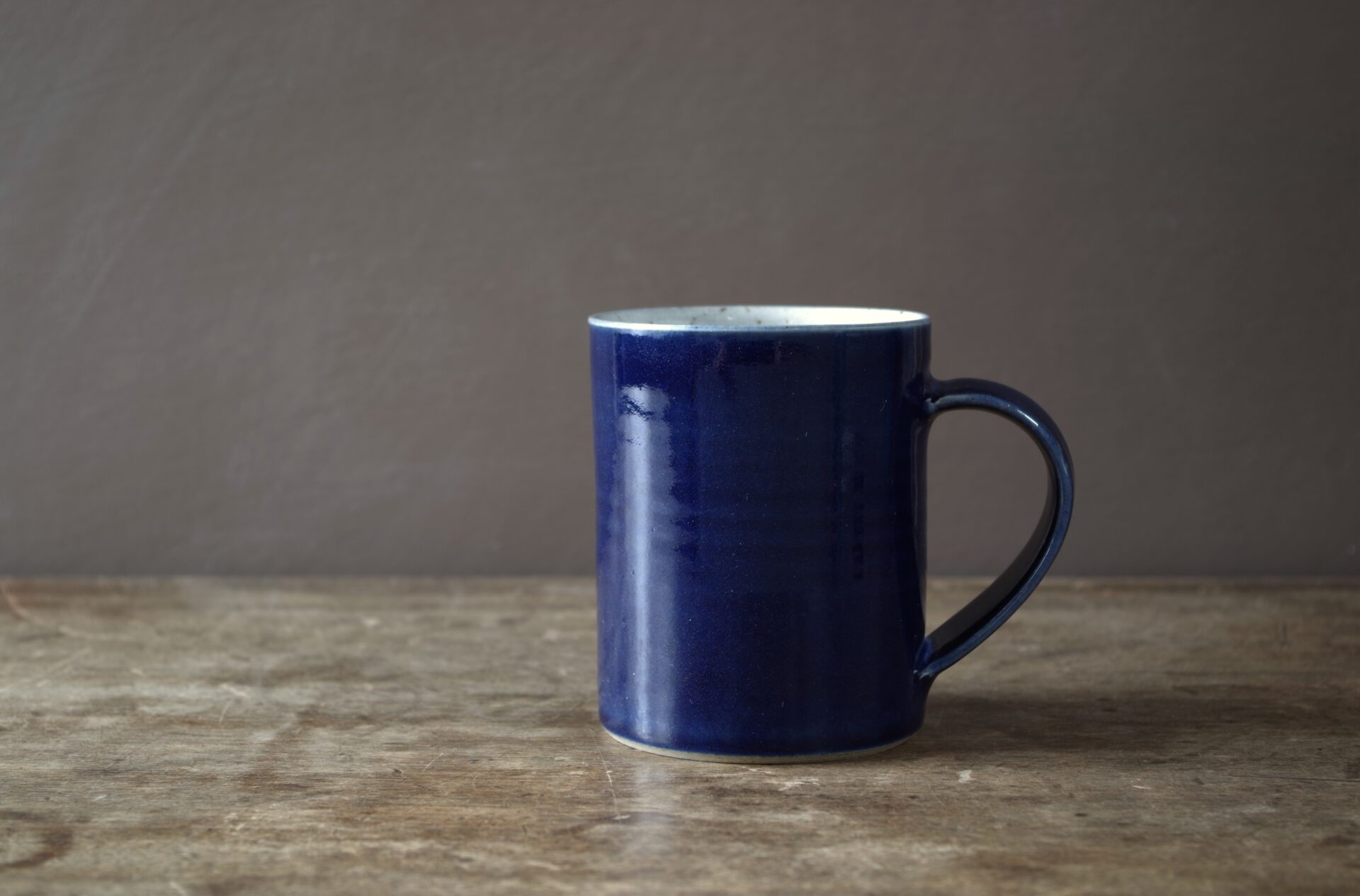 wheel thrown, reduction fired stoneware mug with pulled handle and blue glaze by award winning potters James and Tilla Waters in the studio in Carmarthenshire, Wales UK