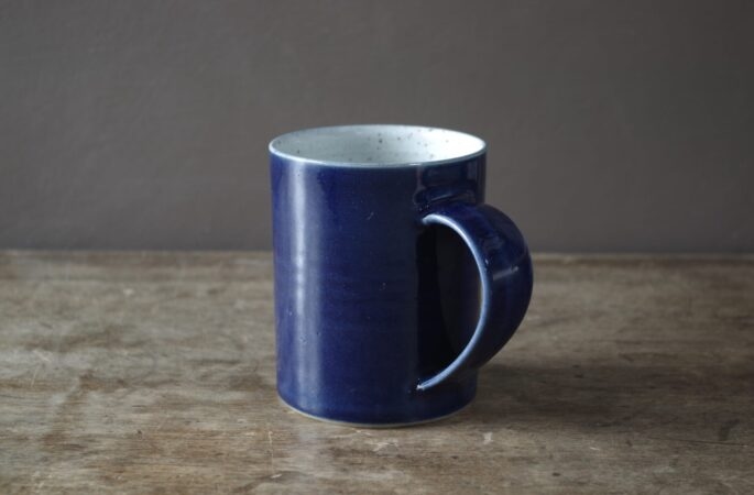 wheel thrown, reduction fired stoneware mug with pulled handle and blue glaze by award winning potters James and Tilla Waters in the studio in Carmarthenshire, Wales UK
