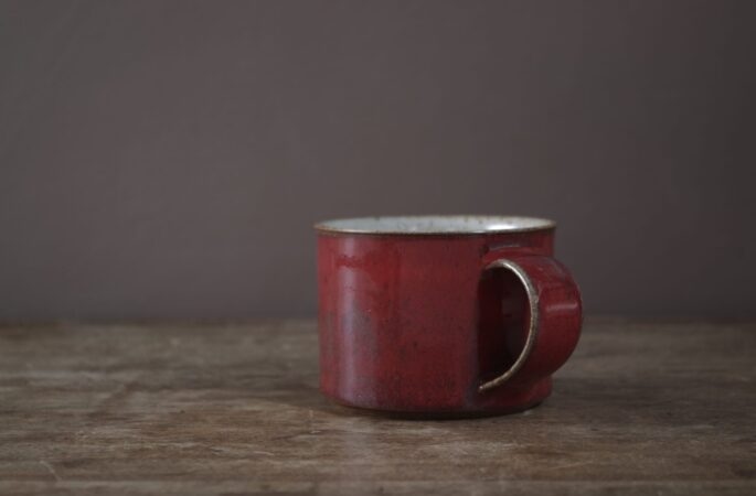 reduction fired, wheel thrown stoneware breakfast mug with pulled handle and copper red glaze by award winning potters James and Tilla Waters in their studio in Carmarthenshire Wales