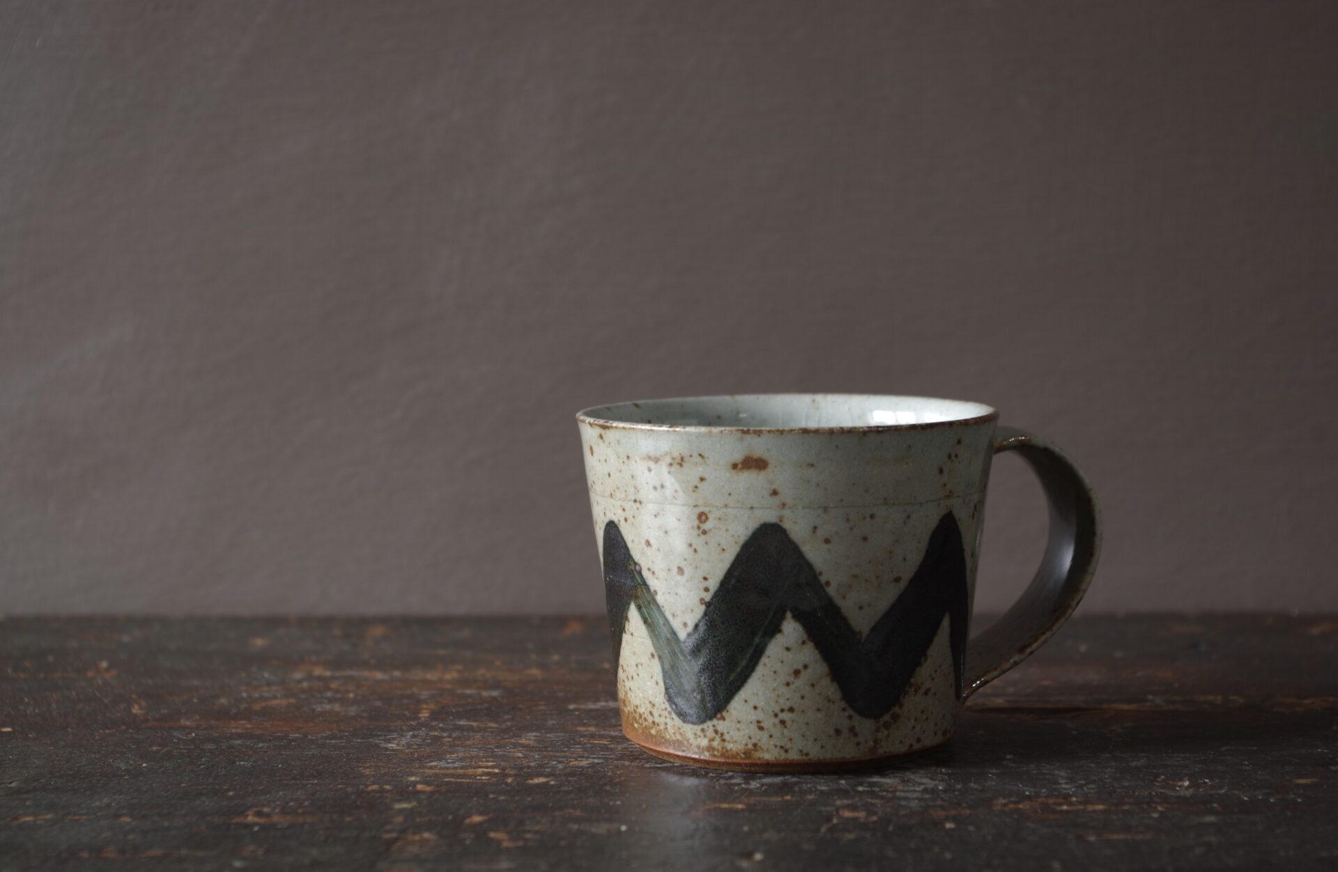 reduction fired, wheel thrown dark stoneware clay flared coffee cup with pulled handle and hand decoration by award winning potters James and Tilla Waters in Carmarthenshire, Wales