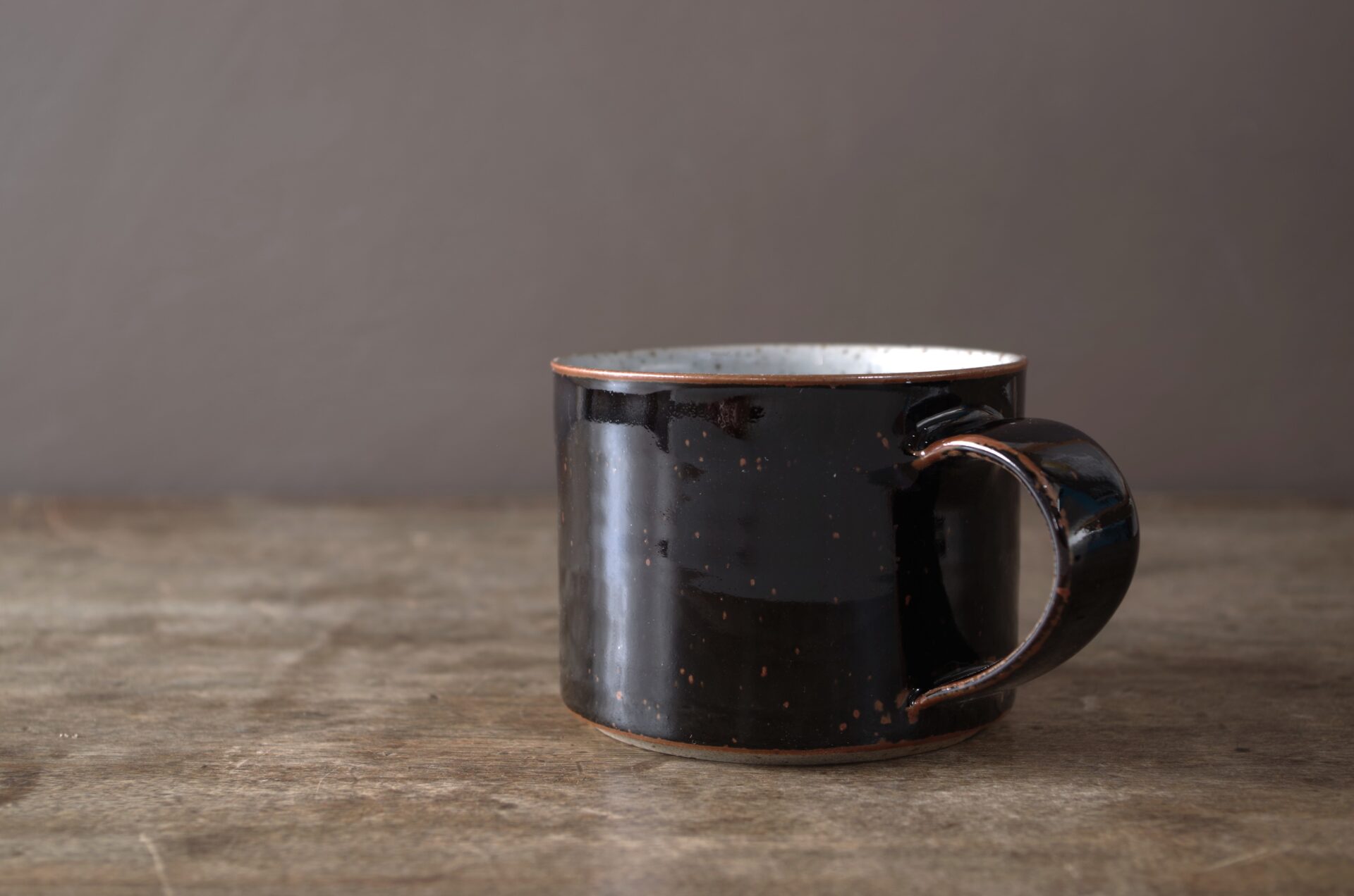 reduction fired, wheel thrown stoneware breakfast mug with pulled handle and tenmoku glaze by award winning potters James and Tilla Waters in their studio in Carmarthenshire Wales
