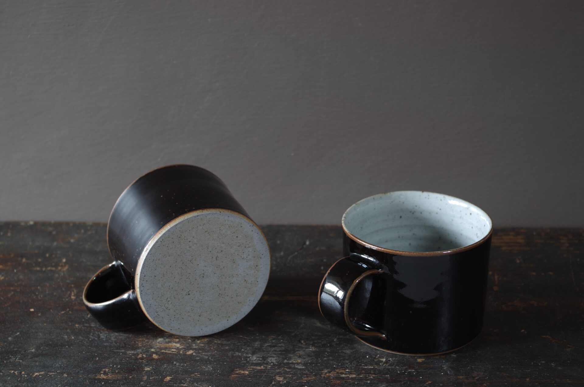 wheel thrown stoneware mug with black tenmoku glaze, pulled handle and reduction fired by award winning studio potters James and Tilla Waters in Carmarthenshire, Wales, UK