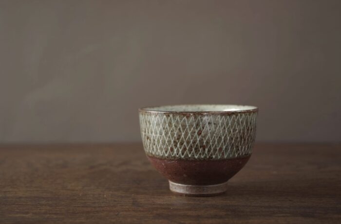 iron rich reduction fired stoneware tea bowl with white inlaid lines by award winning potters James and Tilla Waters in their Carmarthenshire studio in Wales UK