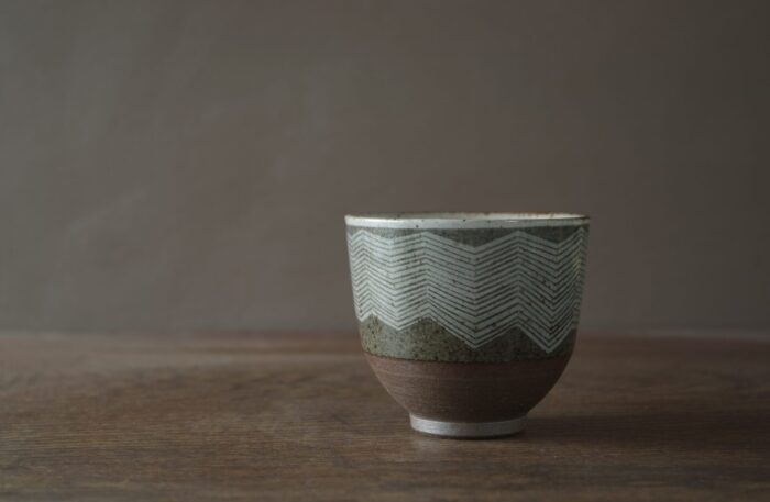 iron rich reduction fired stoneware tea bowl with sgraffito lines and circles by award winning potters James and Tilla Waters in their Carmarthenshire studio in Wales UK