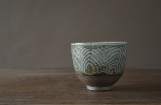 iron rich reduction fired stoneware tea bowl with sgraffito lines and circles by award winning potters James and Tilla Waters in their Carmarthenshire studio in Wales UK