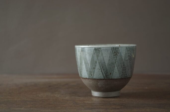 iron rich reduction fired stoneware tea bowl with sgraffito lines and circles by award winning potters James and Tilla Waters in their Carmarthenshire studio in Wales UK