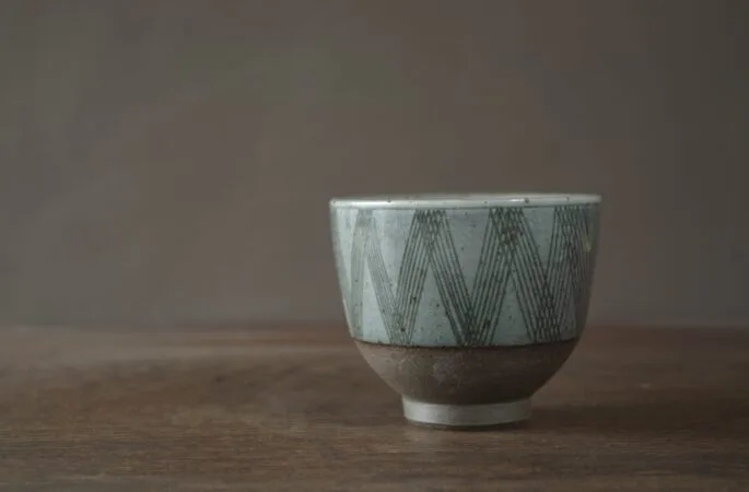 iron rich reduction fired stoneware tea bowl with sgraffito lines and circles by award winning potters James and Tilla Waters in their Carmarthenshire studio in Wales UK