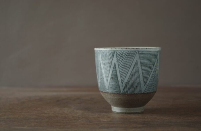 iron rich reduction fired stoneware tea bowl with sgraffito lines and circles by award winning potters James and Tilla Waters in their Carmarthenshire studio in Wales UK