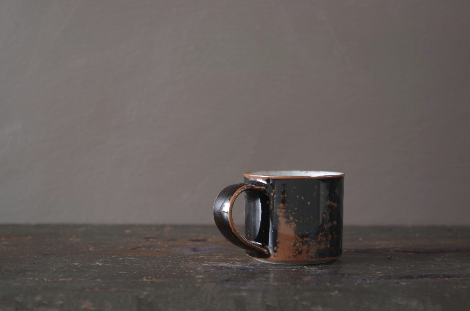 reduction fired wheel thrown stoneware espresso cup with pulled handle and tenmoku glaze by award winning potters James and Tilla Waters in their studio in Carmarthenshire, Wales