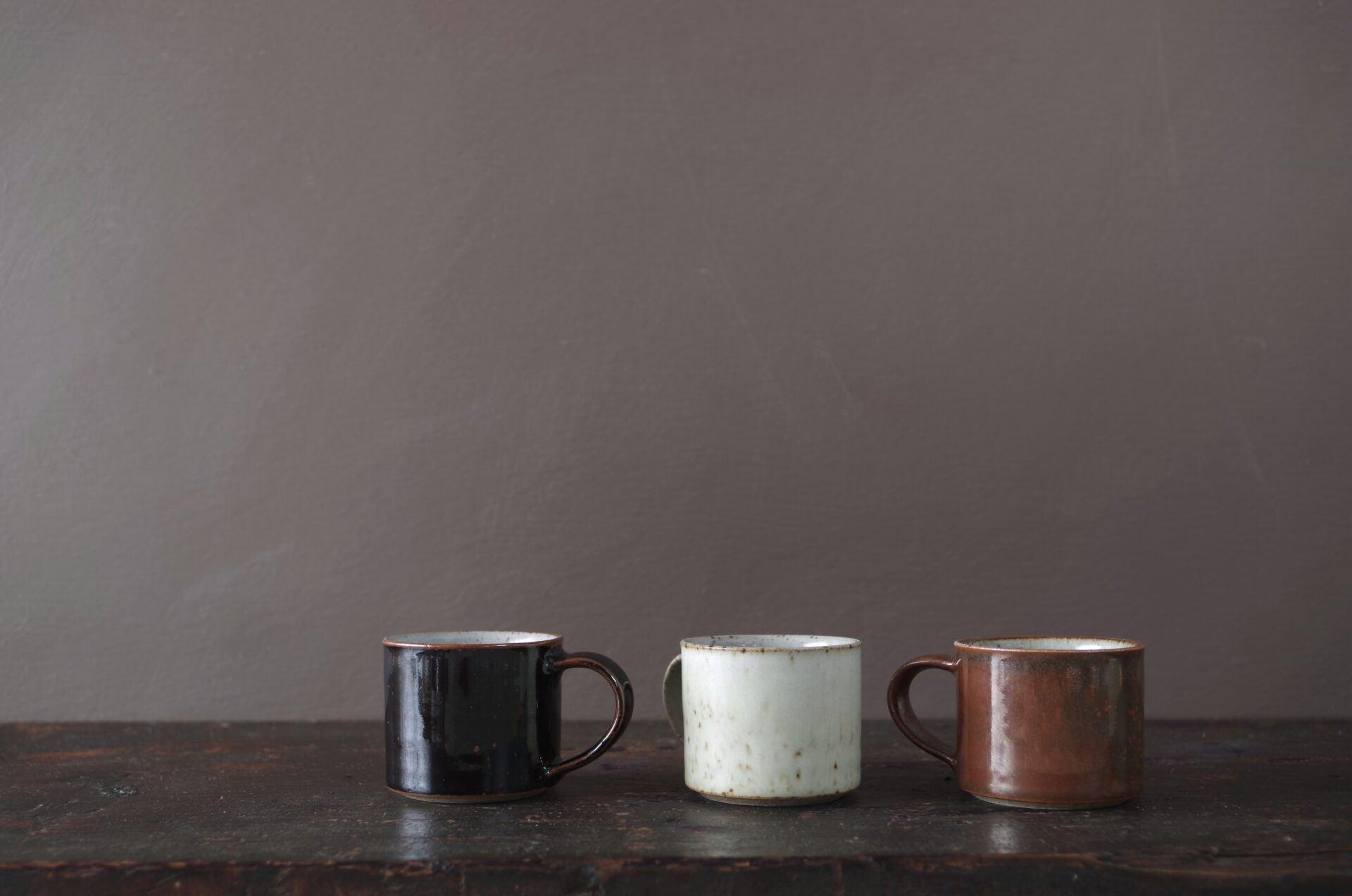 reduction fired wheel thrown stoneware espresso cups with pulled handle and tenmoku glaze by award winning potters James and Tilla Waters in their studio in Carmarthenshire, Wales