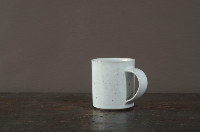 wheel thrown reduction fired stoneware coffee cup with off-white glaze and pulled handle by award winning potters James and Tilla Waters in Carmartheshire, Wales, UK