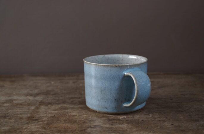 reduction fired, wheel thrown stoneware breakfast mug with pulled handle and pale blue chun glaze by award winning potters James and Tilla Waters in their studio in Carmarthenshire Wales
