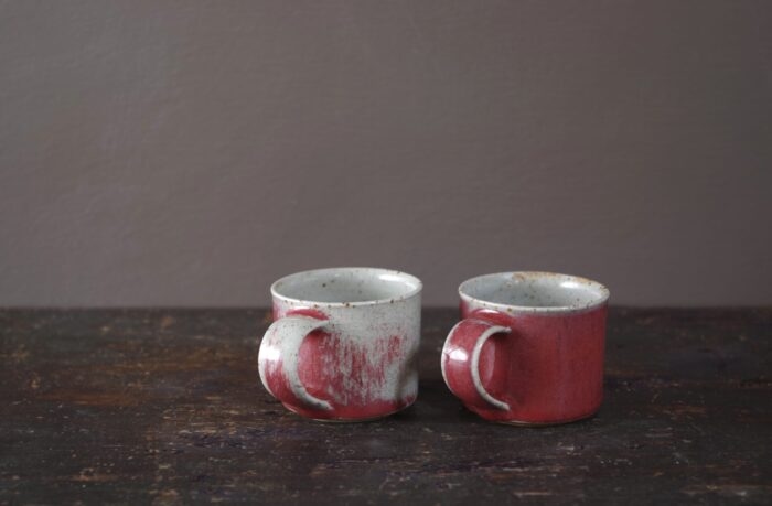 reduction fired wheel thrown stoneware espresso cups with pulled handle and copper red glaze by award winning potters James and Tilla Waters in their studio in Carmarthenshire, Wales