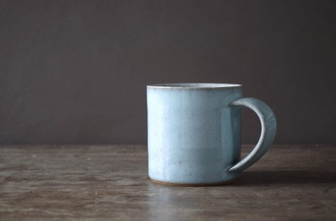 wheel thrown, reduction fired stoneware mug with pulled handle and pale blue chun glaze by award winning potters James and Tilla Waters in the studio in Carmarthenshire, Wales UK