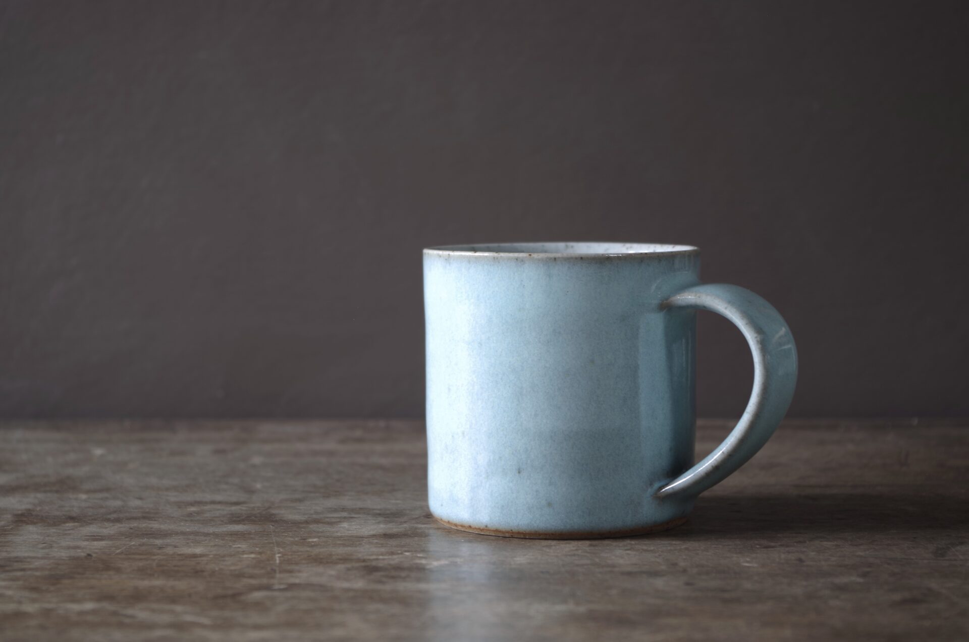 wheel thrown, reduction fired stoneware mug with pulled handle and pale blue chun glaze by award winning potters James and Tilla Waters in the studio in Carmarthenshire, Wales UK
