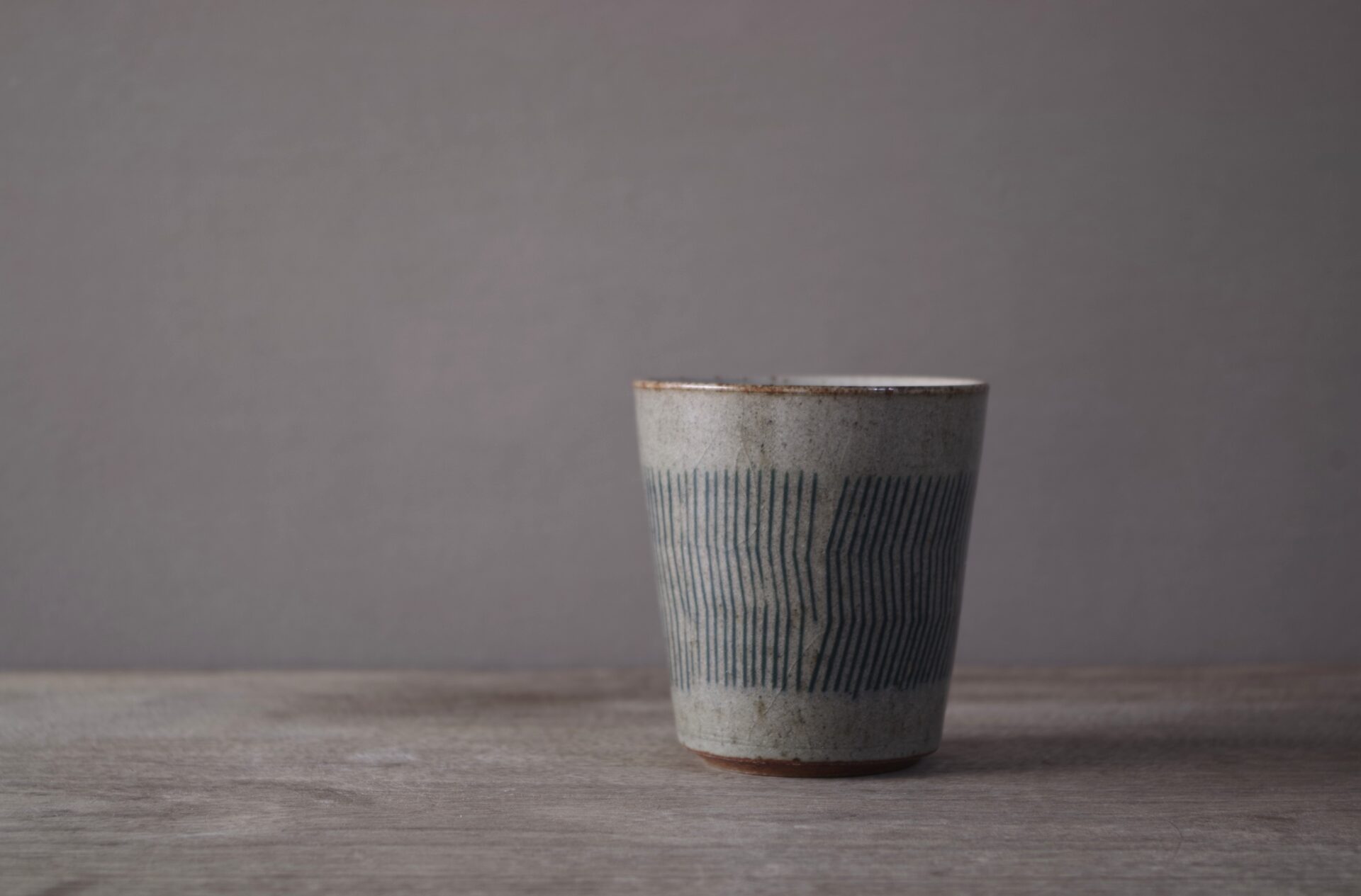 reduction fired stoneware small beaker with inlaid abstract decoration and pulled handle by award winning potters James and Tilla Waters in Carmartheshire, Wales, UK