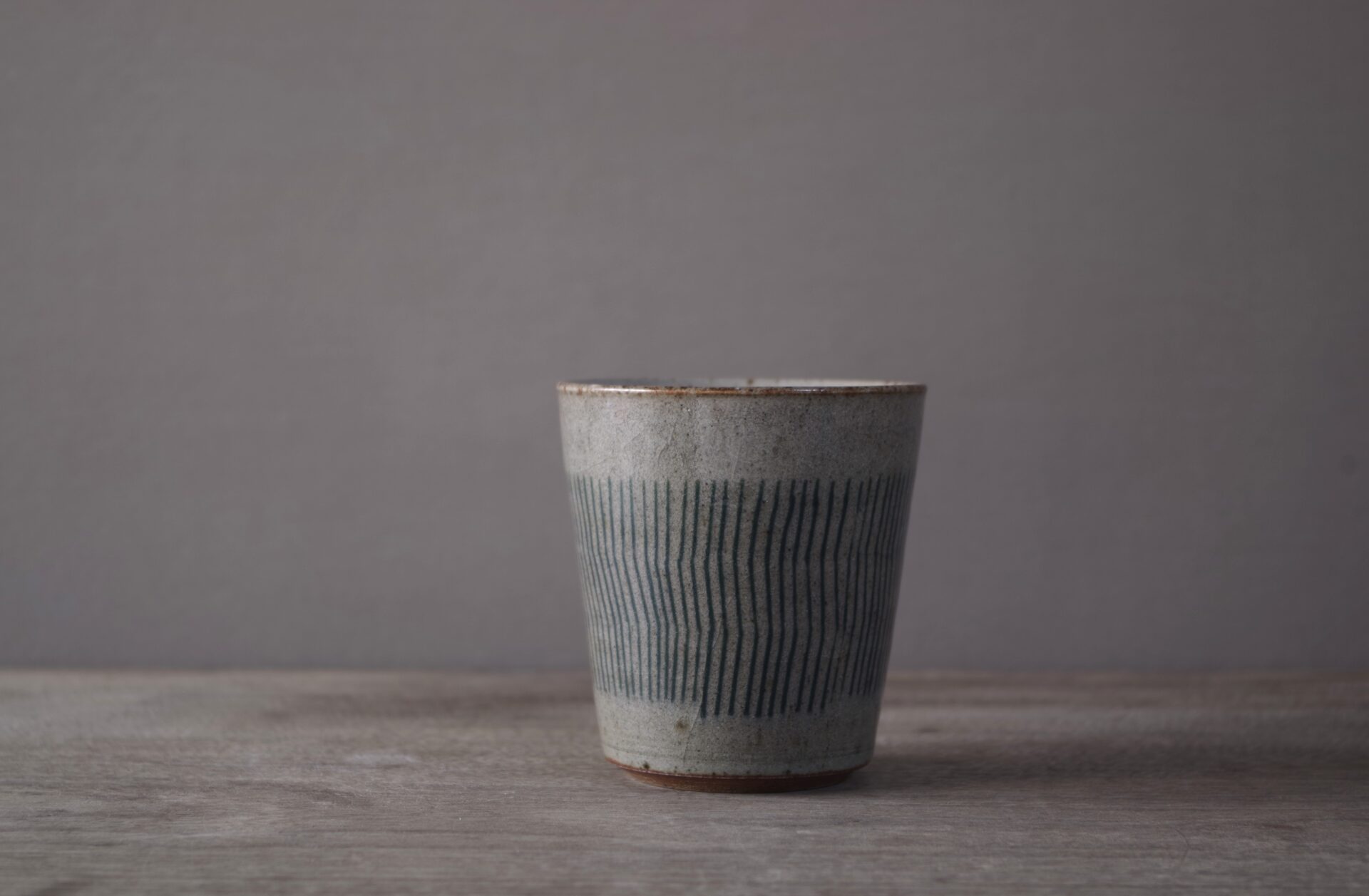 reduction fired stoneware small beaker with inlaid abstract decoration and pulled handle by award winning potters James and Tilla Waters in Carmartheshire, Wales, UK