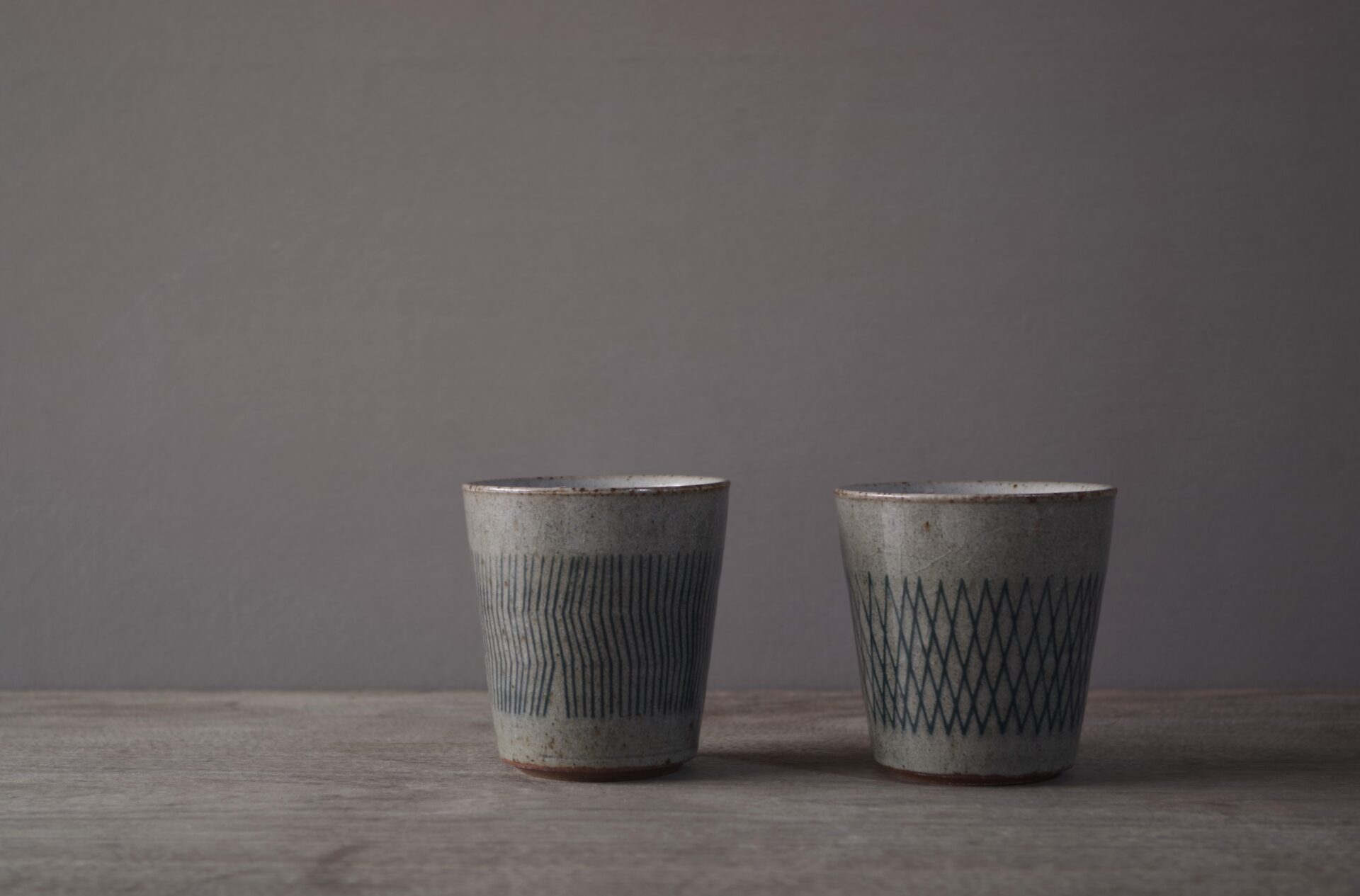 two reduction fired stoneware small beakers with inlaid abstract decoration and pulled handle by award winning potters James and Tilla Waters in Carmartheshire, Wales, UK