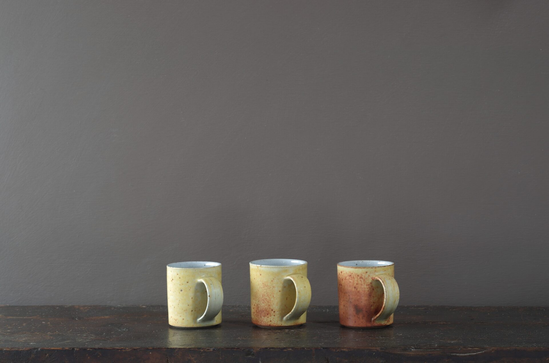 wheel thrown reduction fired stoneware coffee cup with rusty yellow coloured glaze and pulled handle by award winning potters James and Tilla Waters in Carmartheshire, Wales, UK