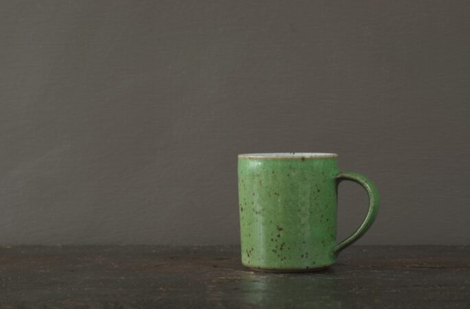 wheel thrown reduction fired stoneware coffee cup with green glaze and pulled handle by award winning potters James and Tilla Waters in Carmartheshire, Wales, UK
