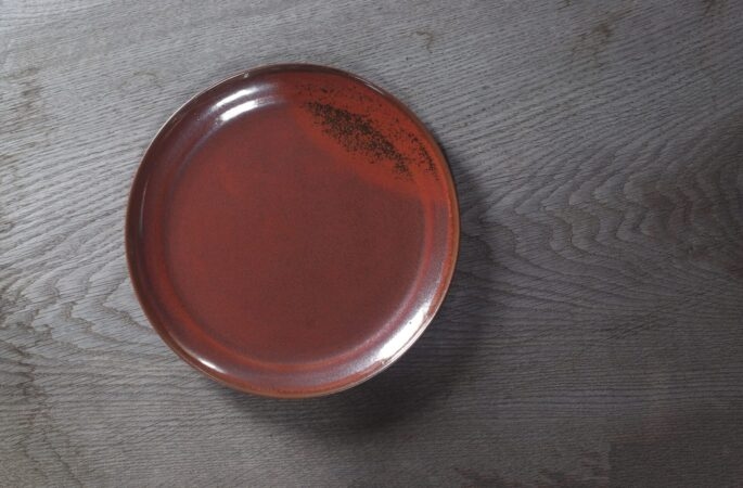 large thrown stoneware dinner plate with persimmon glaze, fired in reduction by award winning studio potters James and Tilla Waters in Carmarthenshire, Wales UK