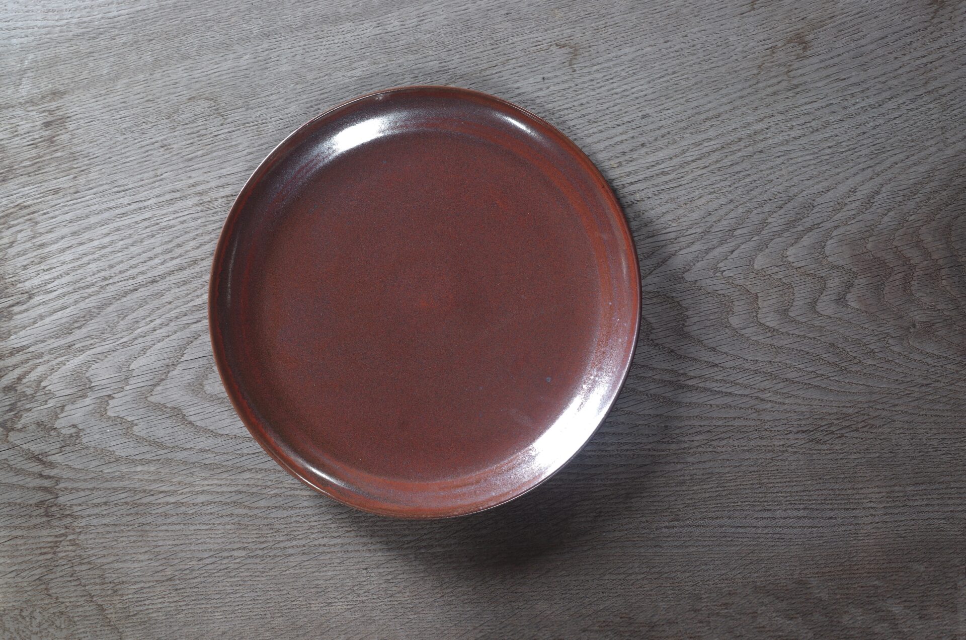 large thrown stoneware dinner plate with persimmon glaze, fired in reduction by award winning studio potters James and Tilla Waters in Carmarthenshire, Wales UK