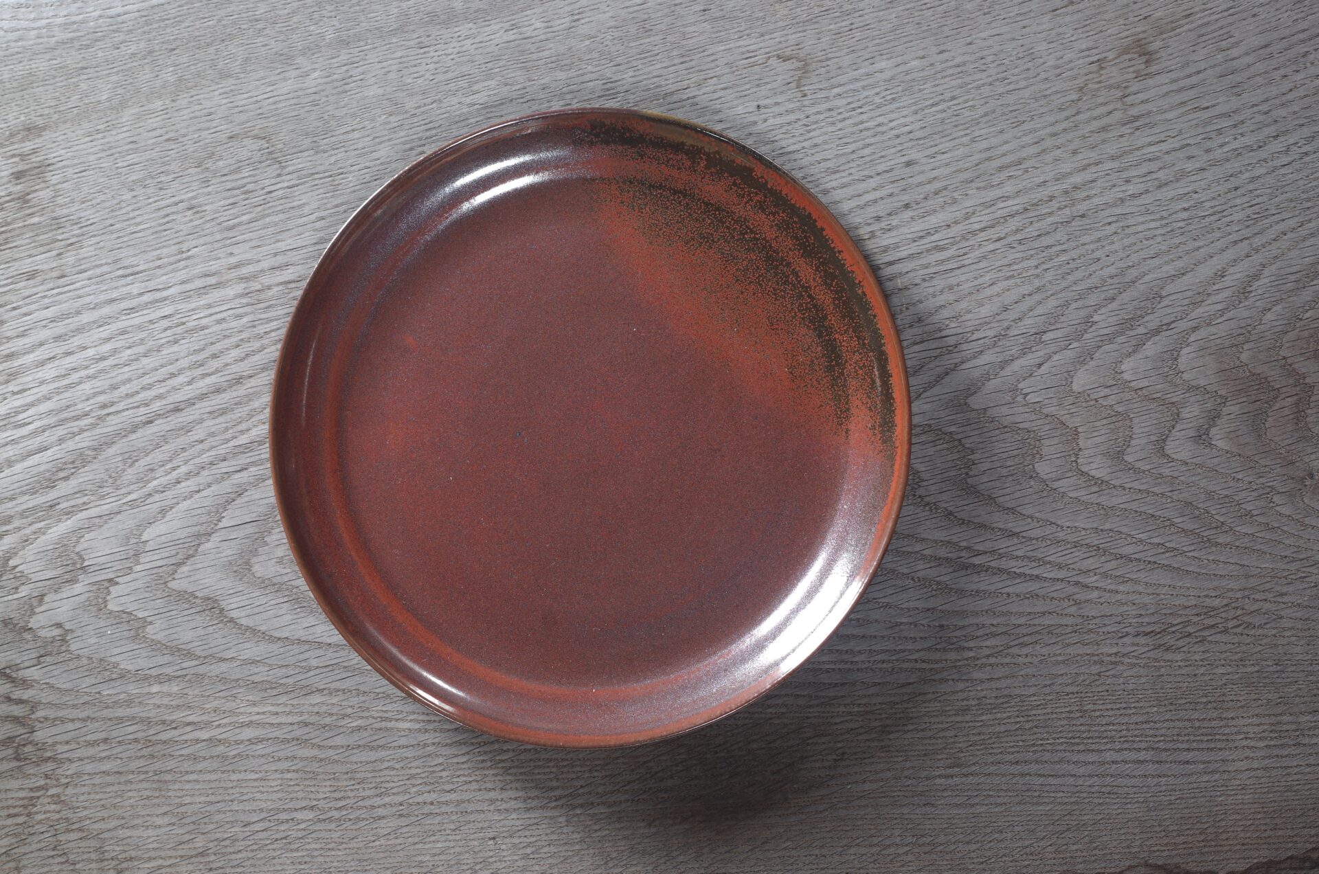 large thrown stoneware dinner plate with persimmon glaze, fired in reduction by award winning studio potters James and Tilla Waters in Carmarthenshire, Wales UK