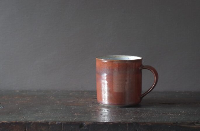 Reduction fired, wheel thrown stoneware "square" (8cm x 8cm) mug with rust coloured persimmon glaze by award winning potters James and Tilla Waters in Carmarthenshire, Wales, UK