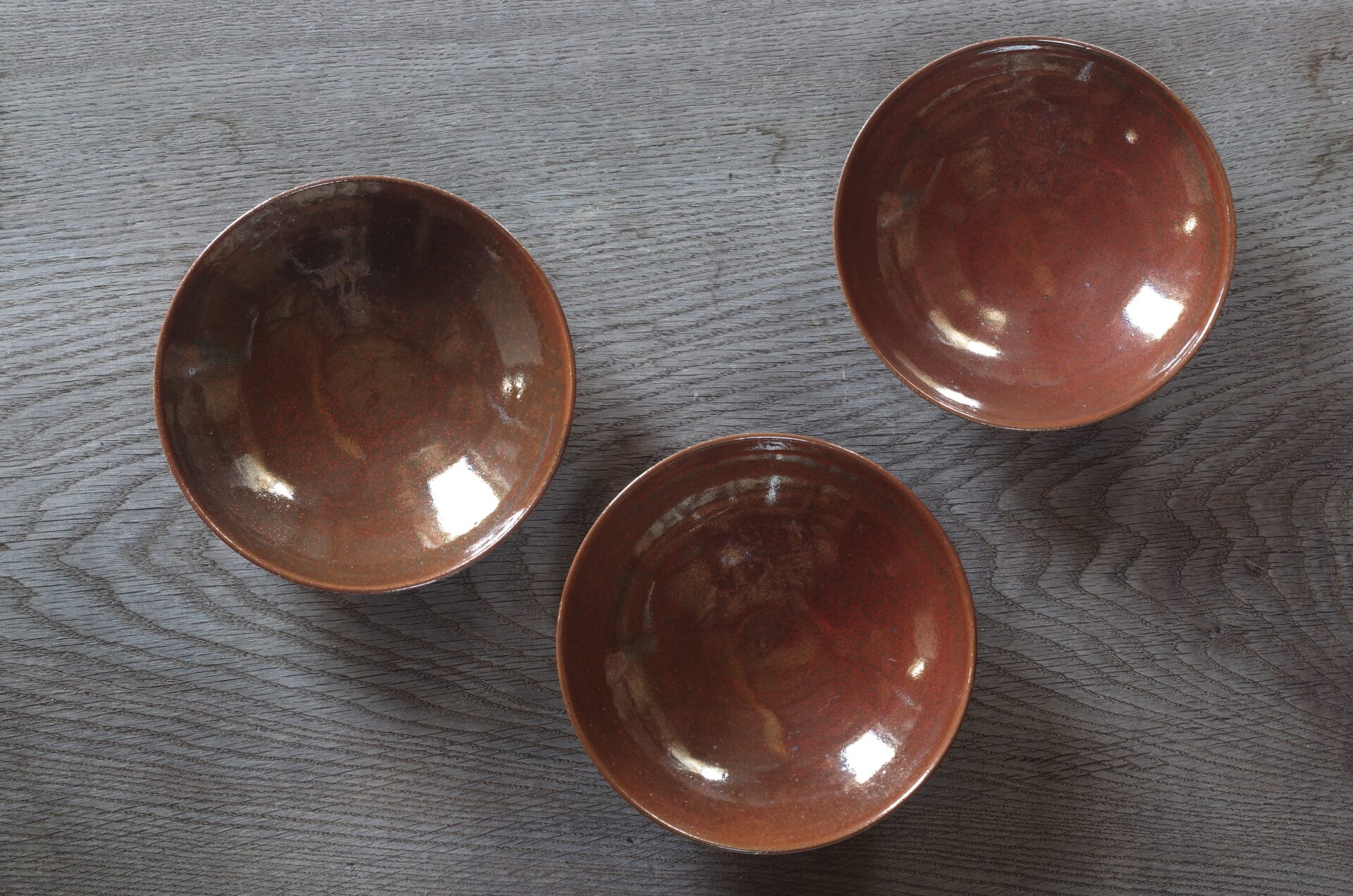 Thrown stoneware open bowl with rust coloured persimmon glaze by award winning potters James and Tilla Waters in Carmarthenshire, Wales, UK