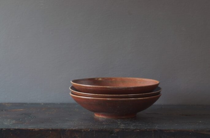 Thrown stoneware open bowl with rust coloured persimmon glaze by award winning potters James and Tilla Waters in Carmarthenshire, Wales, UK