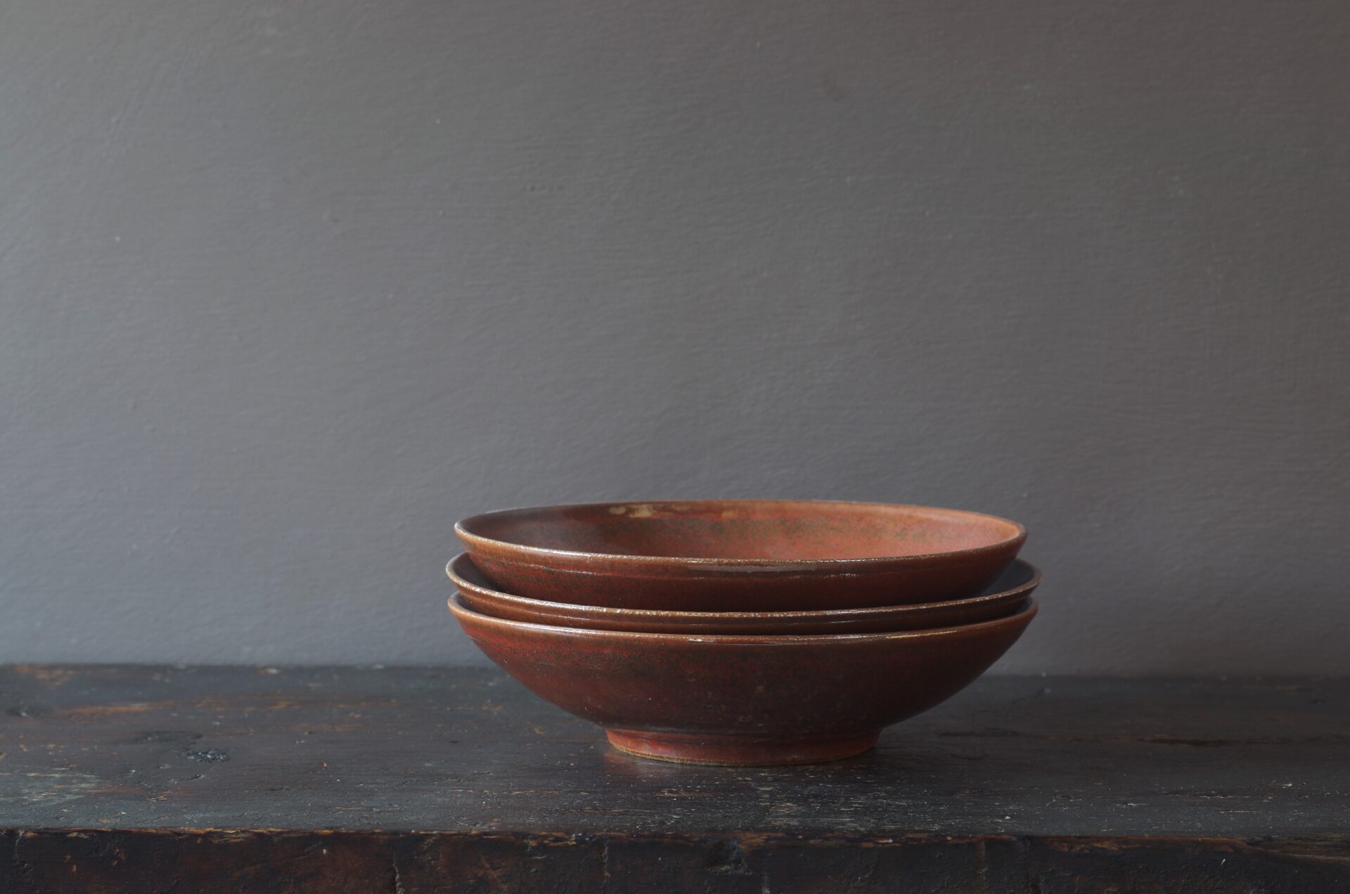 Thrown stoneware open bowl with rust coloured persimmon glaze by award winning potters James and Tilla Waters in Carmarthenshire, Wales, UK